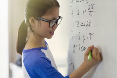 Child doing sums on whiteboard