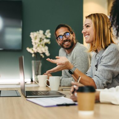 Business woman talking to her colleagues during a meeting in a boardroom. Group of happy business people working together in a creative office.