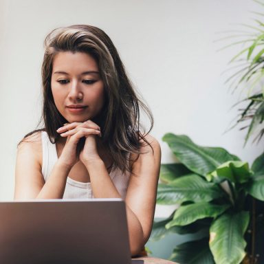 A young Asian woman joining in a video call on her laptop computer.