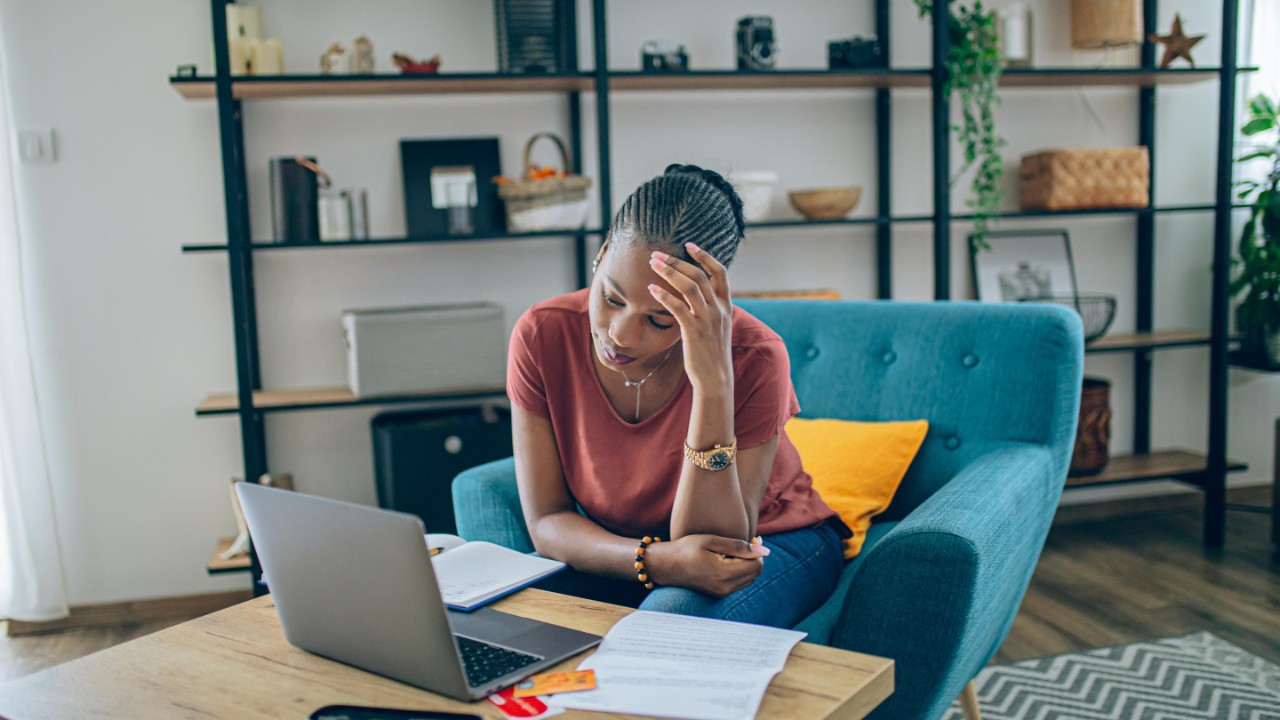 Young African woman taking a break from doing home finances and feeling stressful