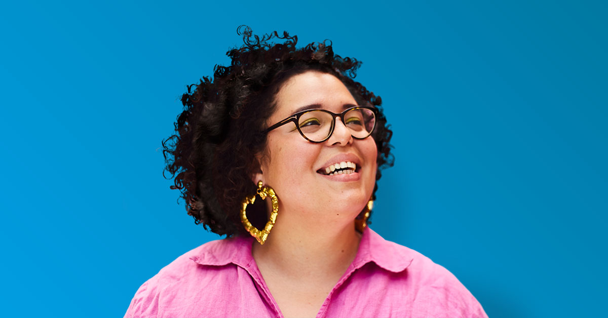 Smiling woman with curly hair, pink blouse, big heart-shaped earrings, glasses - turquoise gradient