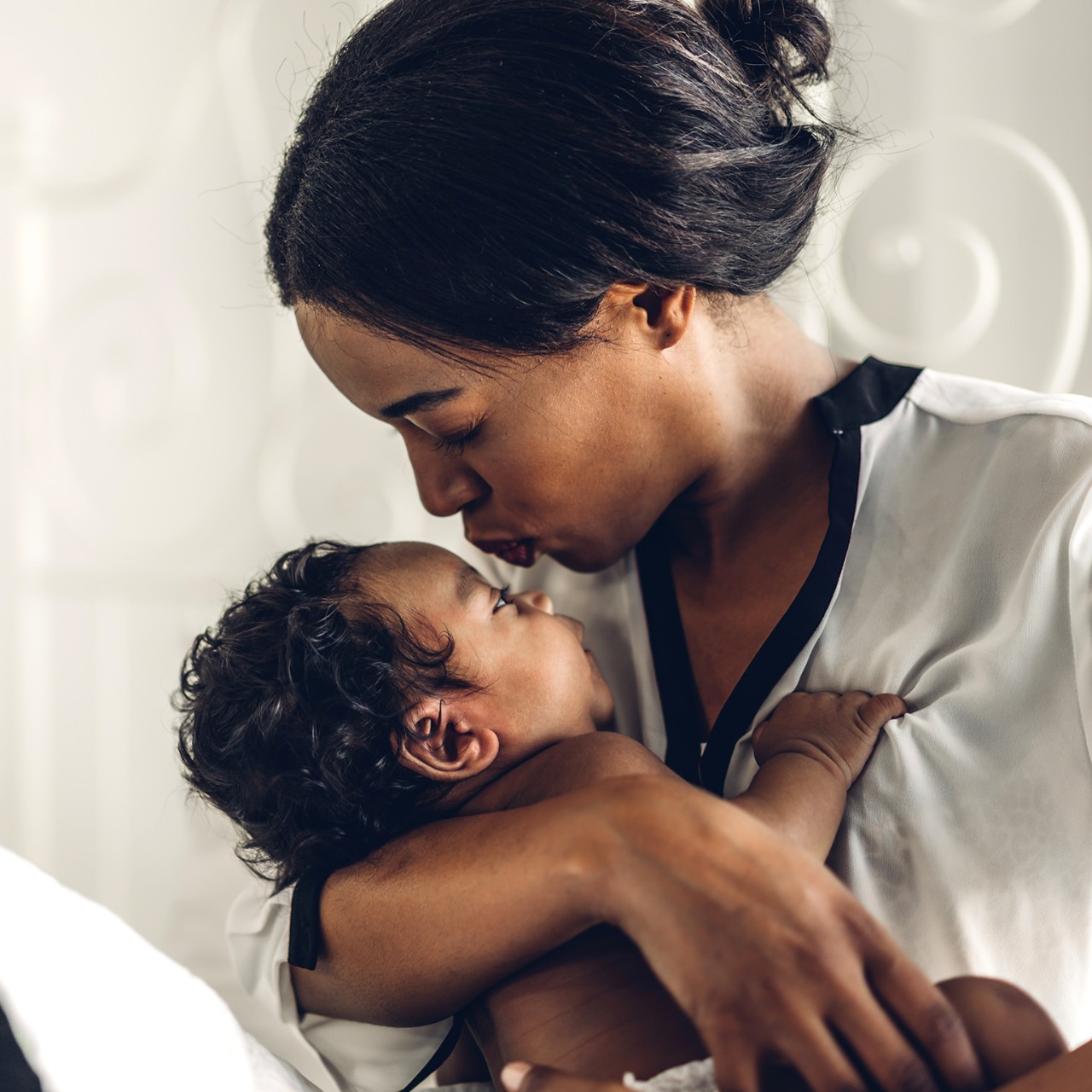 Portrait of enjoy happy love family african american mother playing with adorable little african american baby.Mom touching with cute son moments good time in a white bedroom.Love of black family concept