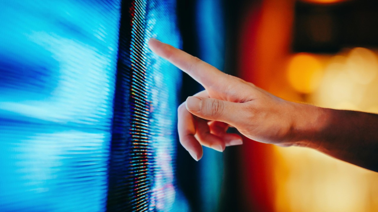 Close up of woman's hand touching illuminated and multi-coloured LED display screen