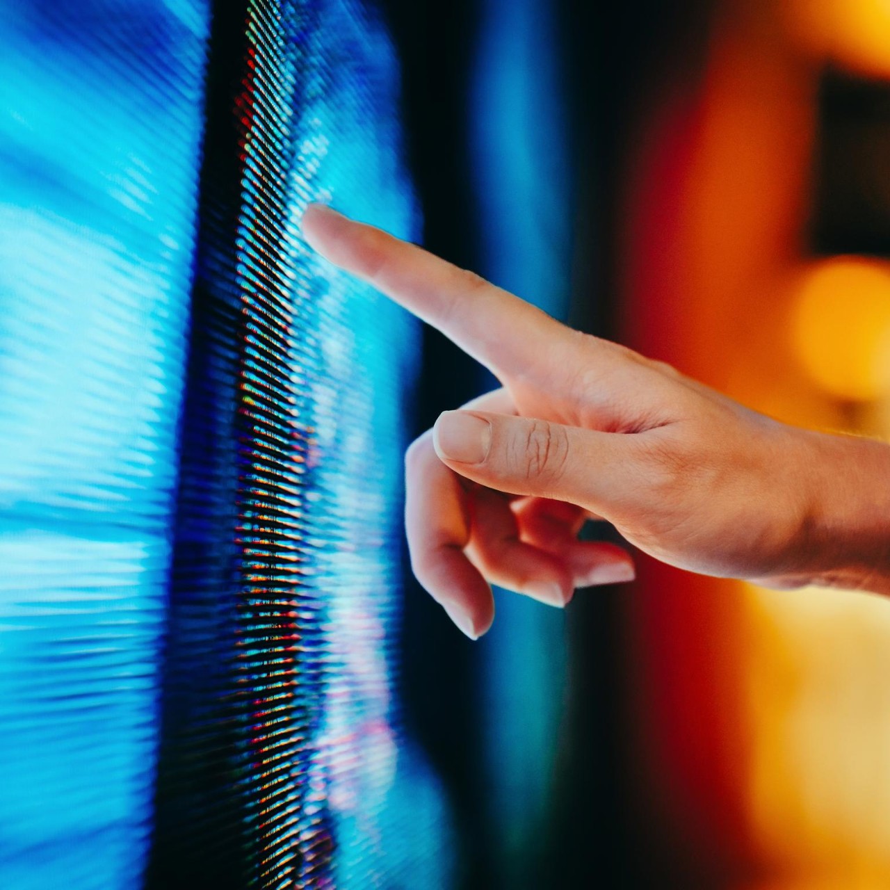 Close up of woman's hand touching illuminated and multi-coloured LED display screen