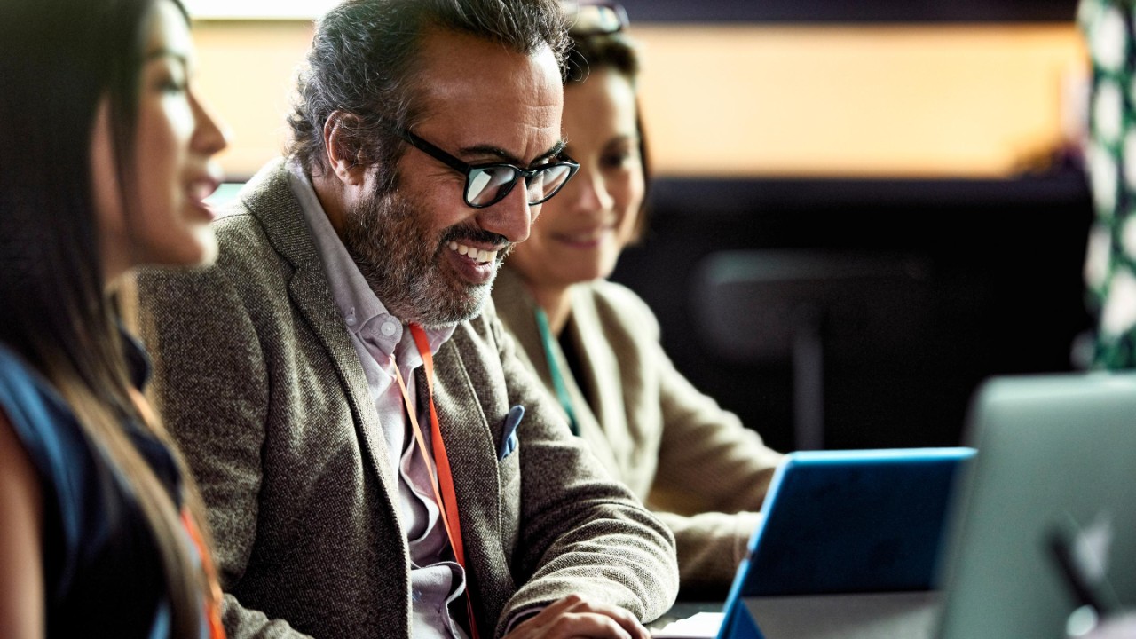 Smiling mature businessman looking at laptop at business meeting