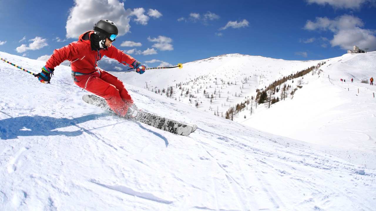 Aktiv man som åker skidor i nedförsbacke 